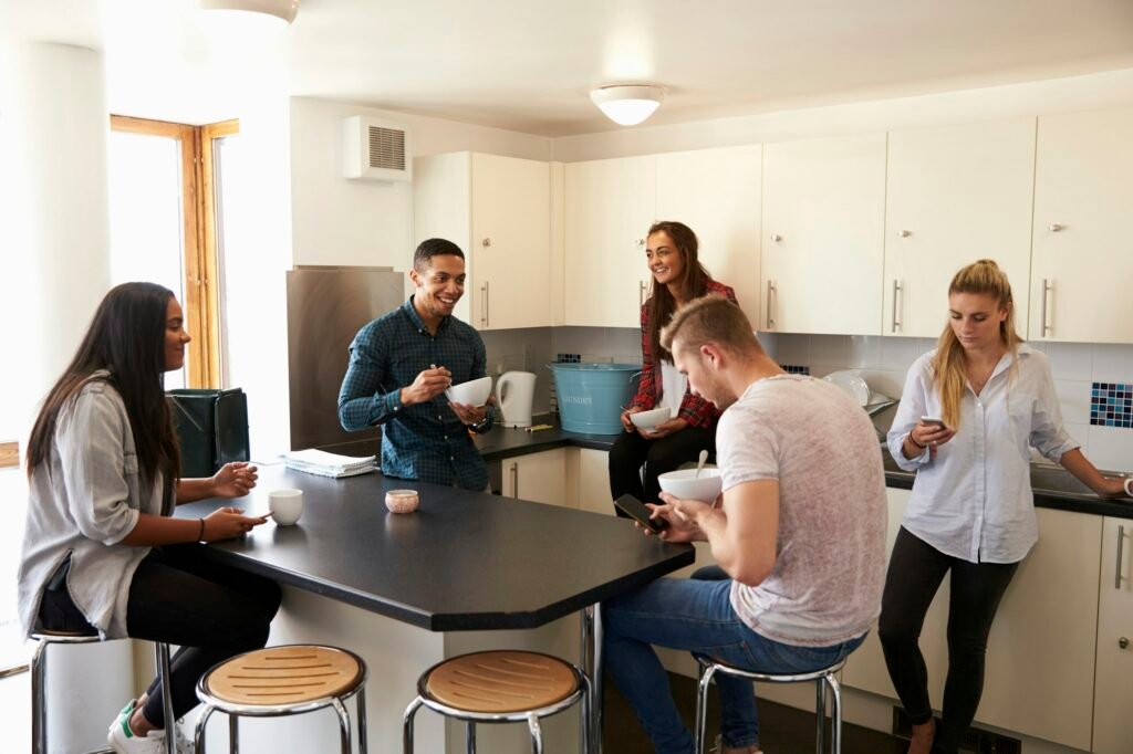 Students Relaxing In Kitchen Of Shared Accommodation