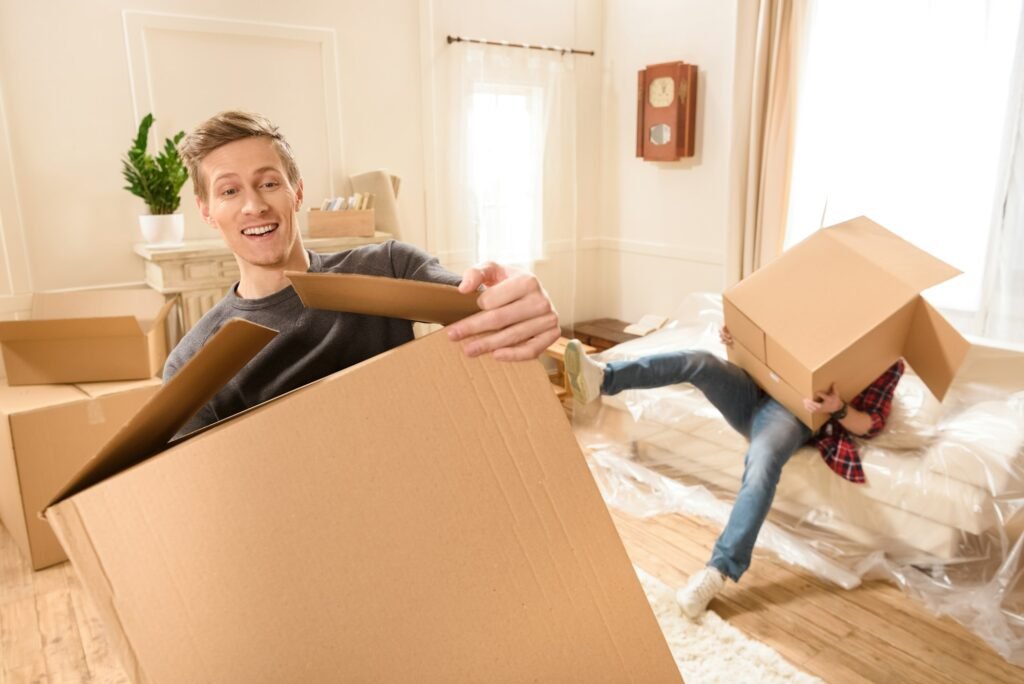 Young friends with cardboard boxes moving into new house